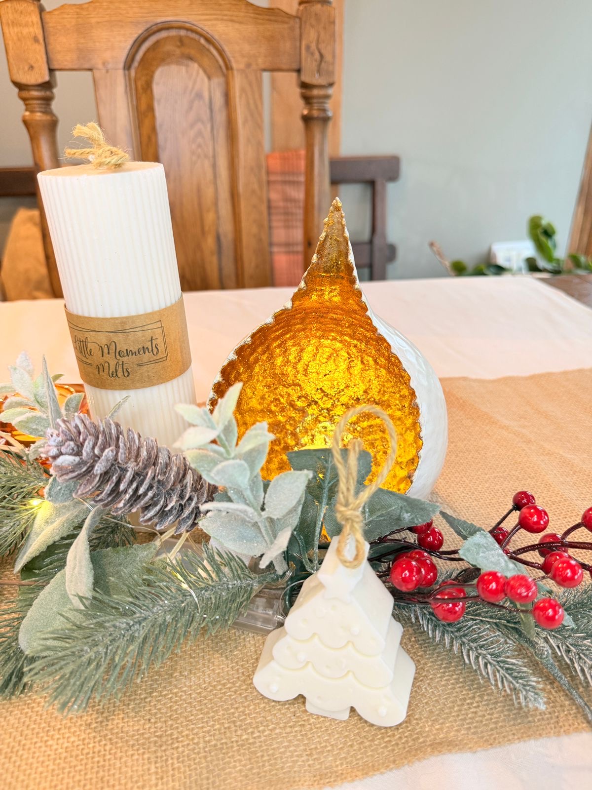 large ribbed pillar candle on a table with a runner, foliage, teardrop candle bowl  and mini candle 