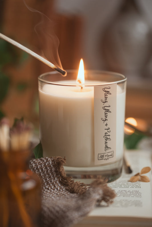 lit candle with lit match beside the wick and matches in the foreground 