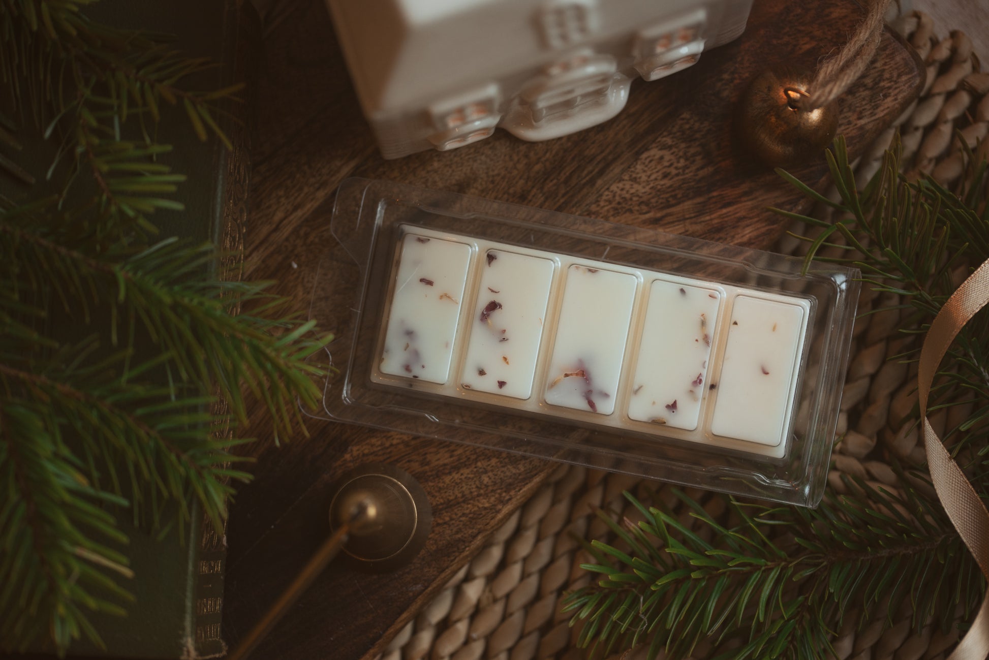 wax melt bar with 5 segments surrounded by fir tree branches and ceramic house wax melt burner 