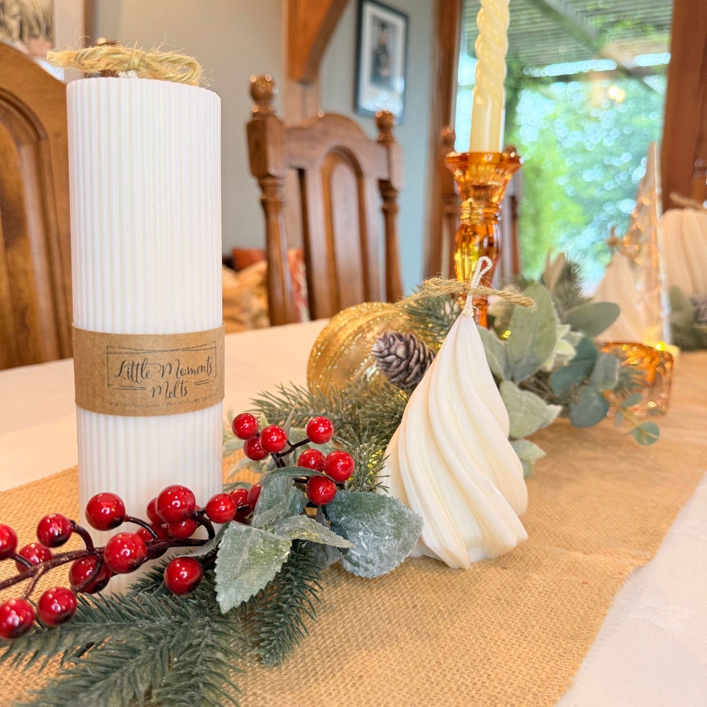 large ribbed  pillar candle on a table with a runner, foliage and mini candle 